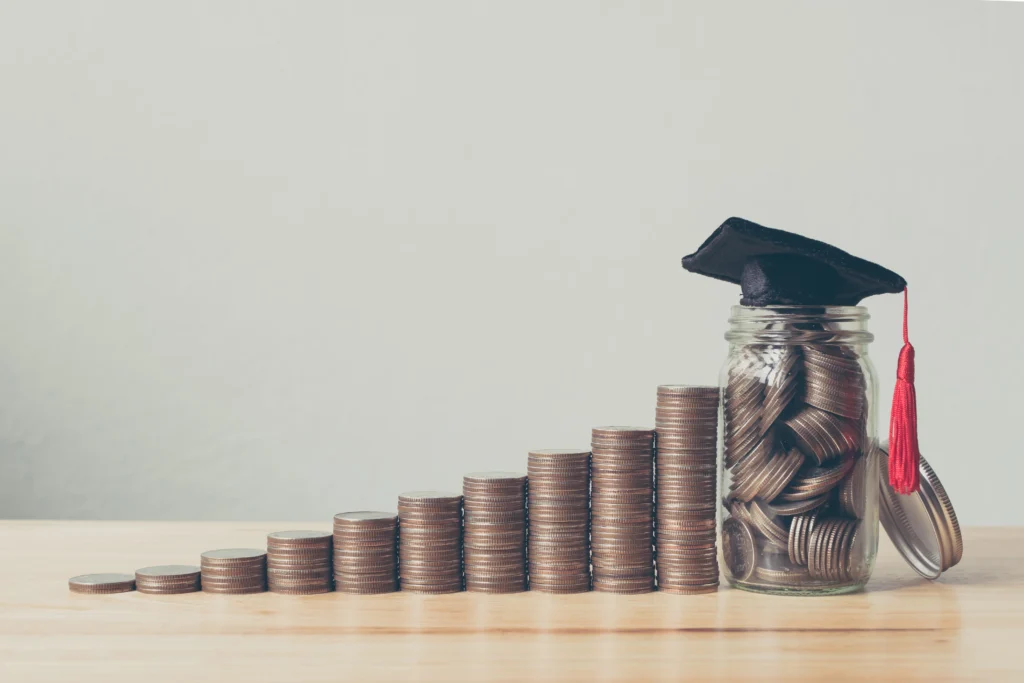 Monedas y un birrete representando los tipos de becas para estudiar en Estados Unidos