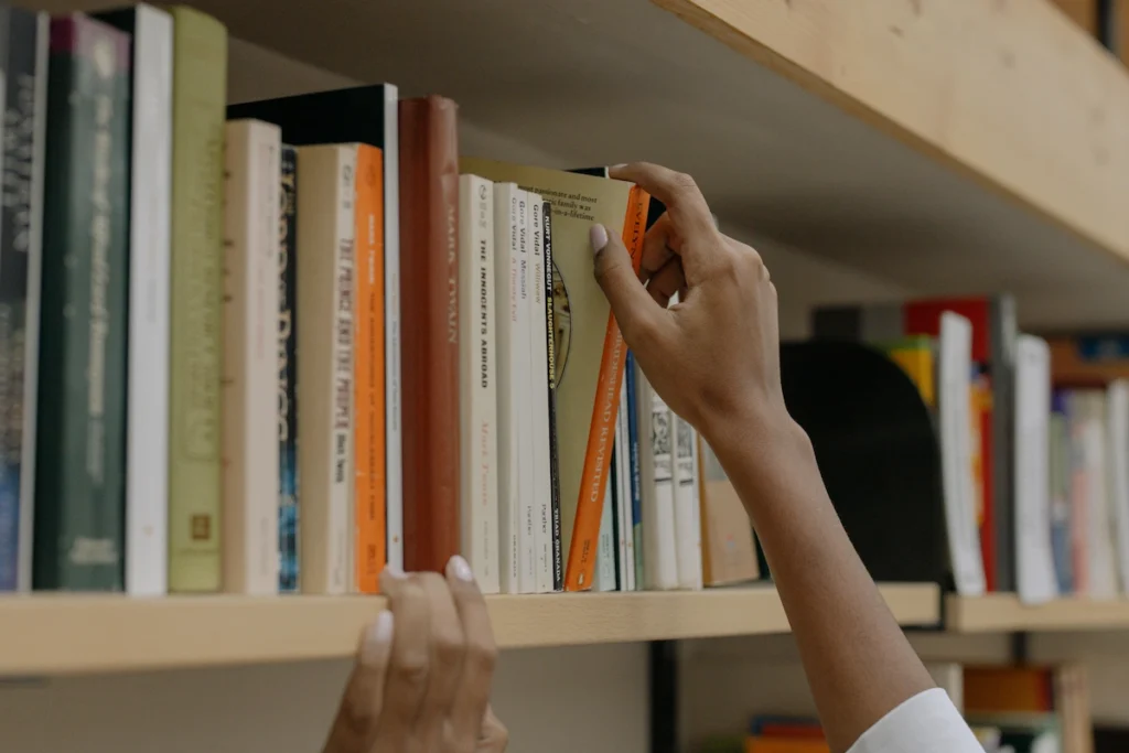 Estudiante seleccionando un libro de una estantería.