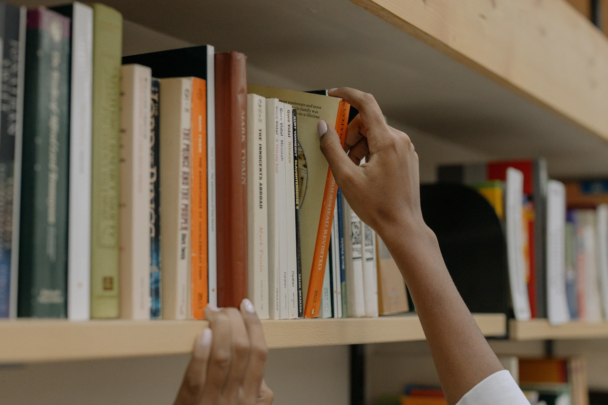 Estudiante seleccionando un libro de una estantería.