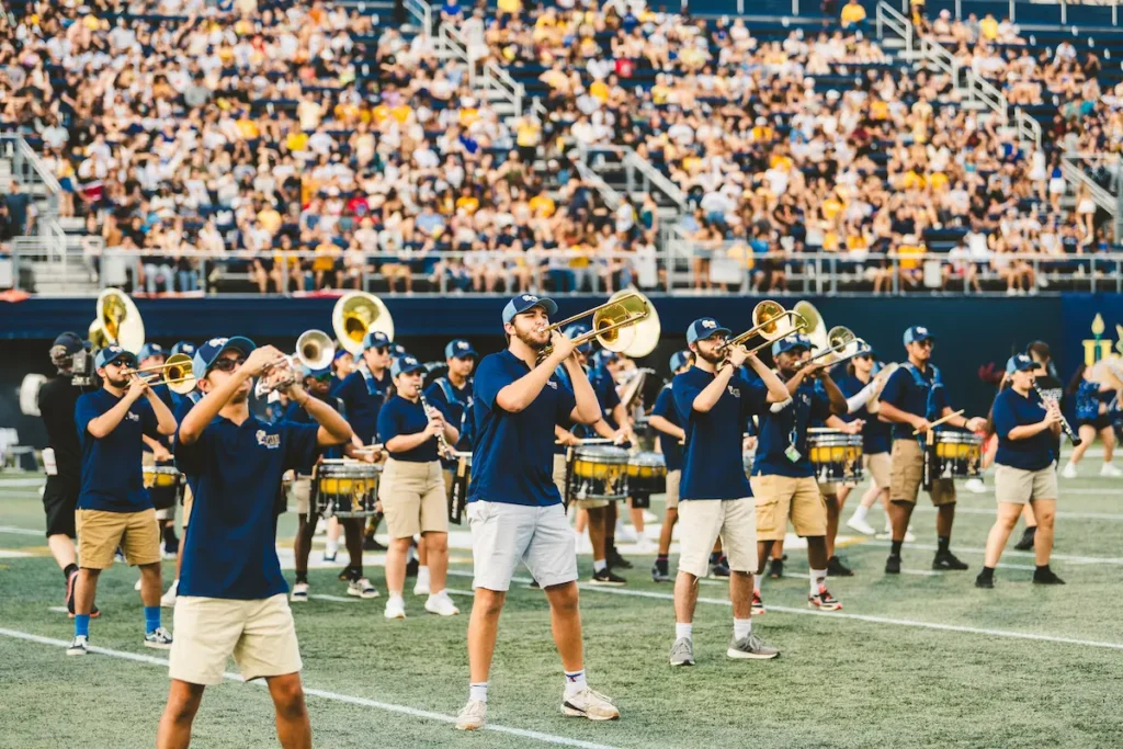 Banda de música tocando durante el medio tiempo de un partido de fútbol americano universitario.