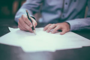 Persona firmando documentos en una mesa