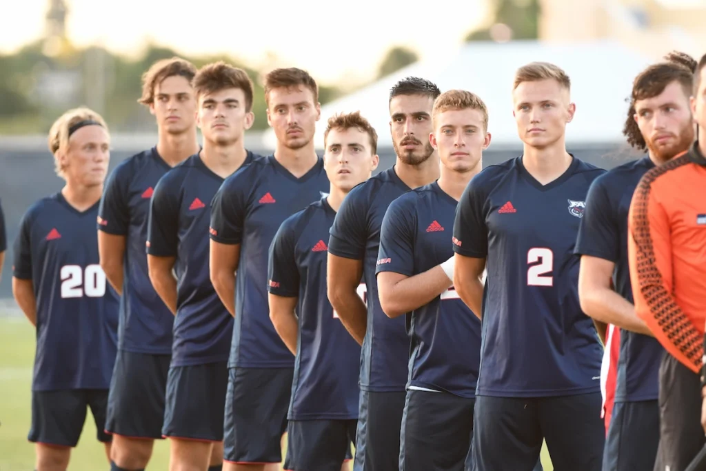 Equipo universitario de fútbol alineado para el himno nacional de Estados Unidos
